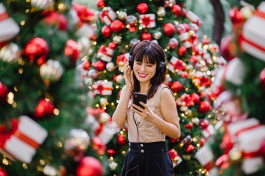 Gün boyunca birkaç süslü Noel ağaçları arasında duran zarif ve çekici bir orta yaşlı kadın portresi