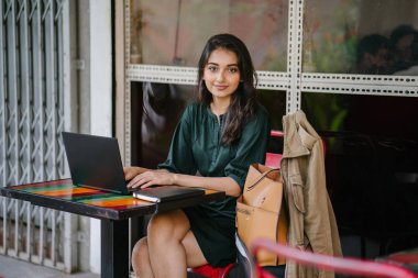 genç üniversite öğrencisi (Hint Asyalı kadın) eğitim ve gün boyunca dizüstü bilgisayar bir masa başında çalışma