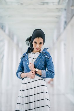 Genç, zarif ve çekici Malezyalı Müslüman kadın gün boyunca elbise ve kot ceket giyiyor..