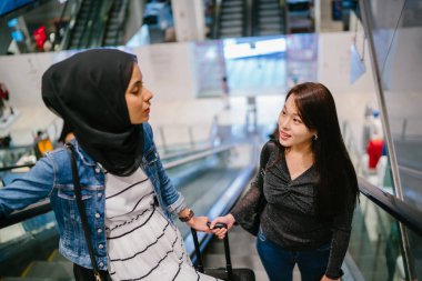 İki arkadaş, Orchard Road, Singapur, Asya 'da aydınlık bir yaz gününde mutlu bir şekilde yürüyüp konuşurlar. Biri Müslüman Malezyalı, diğeri Çinli bir kadın.. 