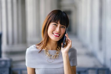 Çekici, kendine güvenen ve başarılı bir Çinli Asyalı kadının portresi. Akıllı telefonuyla konuşuyor. 