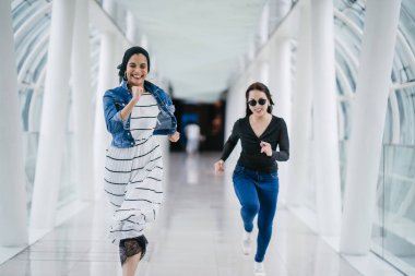 İki farklı arkadaş, iyi aydınlatılmış beyaz fütüristik bir üstgeçit köprüsünden kameraya doğru koşuyorlar. Biri Müslüman bir Orta Doğulu kadın, diğeri de Çinli..