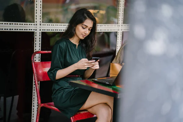 年轻的新加坡印度妇女检查她的智能手机 因为她休息从学习或工作在她的笔记本电脑在白天在咖啡馆 — 图库照片
