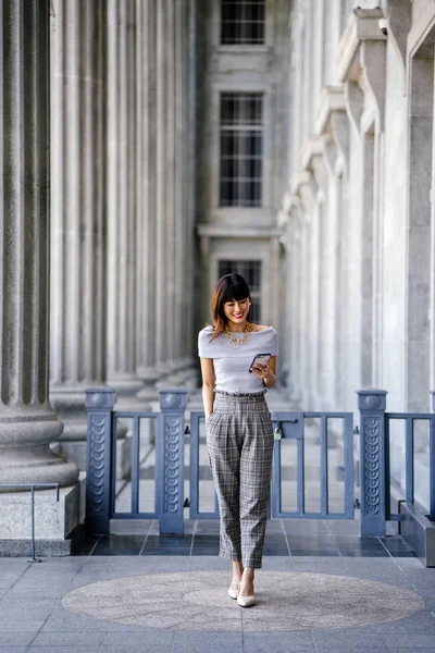 Çekici, kendine güvenen ve başarılı bir Çinli Asyalı kadının portresi. Akıllı telefonunu tutuyor. 