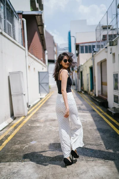 Genç, uzun boylu, ince ve zarif Hint Asyalı kadın rahat bir kıyafet içinde Asya bir sokakta bir sokakta aşağı gün boyunca yürür