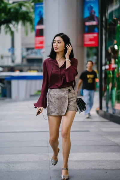 美丽的韩国女人穿着一件优雅的衬衫和短裤跳舞 她走在城市的街道上 戴着耳机 — 图库照片