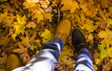 Kadın ve erkek ayak Boots sarı sonbahar akçaağaç yaprakları sonbaharda stand..