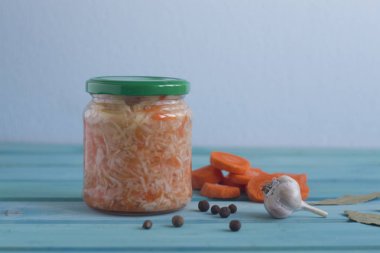 Bir kavanoz ve sarımsak ve defne yaprakları parlak mavi zemin üzerine lahana turşusu fotoğraflar. Fermente sebze.