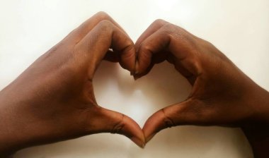 Afrikalı kadının elleri bembeyaz bir aşk kalbi oluşturuyor. Gölgeler. Sade. Kahverengi renk. Aşk konsepti.