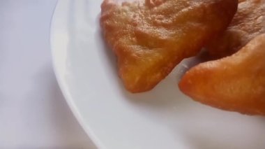 Mandazi beyaz plaka kaydırağında çekim yapıyor. Yukarı doğru hareket. Göster. Afrika mutfağı. Video klibi. Kahverengi renkli.