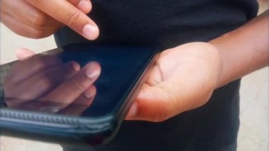 Siyah tableti seçen bir adamın ellerini tıklatıp sonra da yan düğme görüntülerine basarak yakınlaştır. Dokunmatik ekranda kaydırma ve tablet video klibini döndürme. - Süper. Sıradan giyinmiş Afrikalı bir adam. Orta parmağını kullanarak tarar ve seçer. 