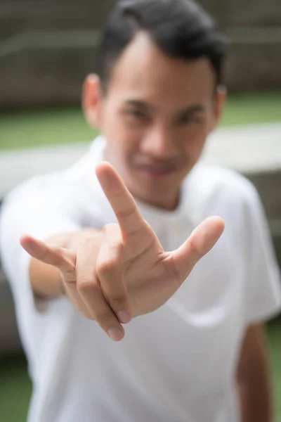 man with love or rock hand gesture; asian man showing love hand sign or rock hand sign; asian young adult man model