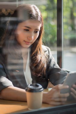 bilgisayar tablet kullanan iş kadın; Onun kullanışlı taşınabilir bilgisayar tablet vasıl seyir işkadını çalışma, holding, resmi kıyafetli portresi; Asyalı Genç Yetişkin kadın modeli