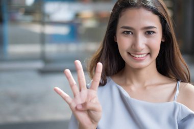 mutlu kız sayı 4 parmak işaret; neşeli mutlu gülümseyen Asyalı kadın el dört parmak ile işaret eden oktan yukarı portresi; sayı kavramı dört, 4 puan, ileri yerleştirin; Asyalı kadın genç yetişkin modeli
