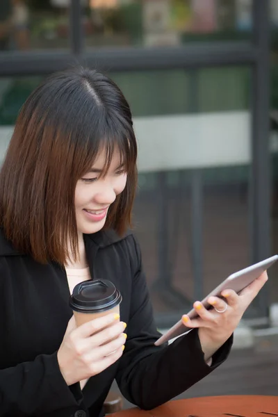 happy business woman using computer tablet; portrait of happy smiling positive successful businesswoman in formal suit working, looking at her mobile computer tablet; asian chinese young adult woman model