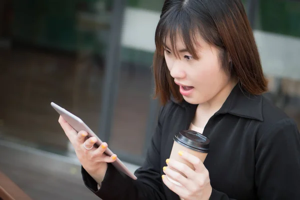 happy laughing business woman using computer tablet; portrait of excited surprised happy laughing business woman in suit working with her mobile computer tablet; asian Chinese young adult woman model