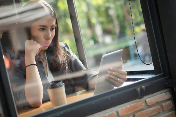 happy laughing business woman using computer tablet; portrait of excited surprised happy laughing business woman in suit working with her mobile computer tablet; south east asian adult woman model