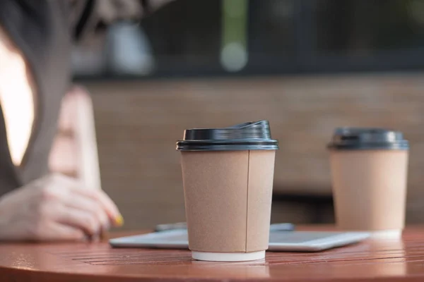 coffee break for casual business meeting; close up of paper coffee cup on casual business meeting table in cafe