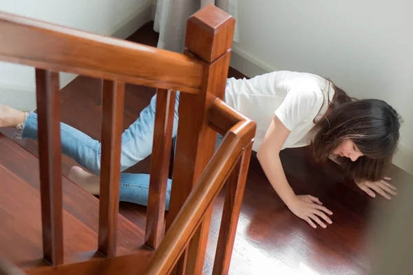 injured woman with hip pain or back injury; portrait of asian woman falling from stair, having pain at her back or hip, concept of pain or injury from accident; 30s adult asian woman model