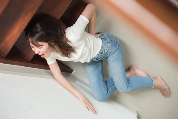 injured woman with hip pain or back injury; portrait of asian woman falling from stair, having pain at her back or hip, concept of pain or injury from accident; 30s adult asian woman model