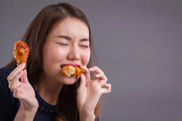 woman eating unhealthy fat fried chicken; portrait of unhealthy girl eating fat fried chicken, fast food; unhealthy eating, dining with high cholesterol fat concept; asian chinese 20s woman model