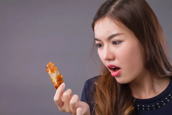 woman eating unhealthy fat fried chicken; portrait of unhealthy girl eating fat fried chicken, fast food; unhealthy eating, dining with high cholesterol fat concept; asian chinese 20s woman model