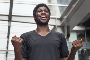 Güçlü başarılı Afrika adam portre; olumlu ifade güçlü kendine güvenen genç yetişkin Afrika adam gülümseyerek mutlu, heyecanlı sürpriz ifade; Afrika Genç yetişkin adam modeli
