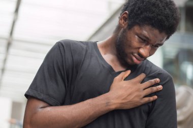 Kalp krizi ya da göğüs ağrısı olan hasta Afrikalı bir adam; kalp krizi geçiren Afrikalı bir adamın portresi, göğüs ağrısı, sağlık sigortası konsepti; genç bir Afrikalı erkek ya da zenci adam modeli