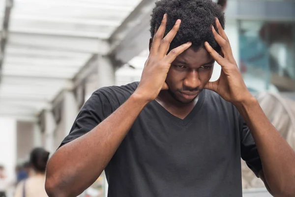 portrait of stressed sick african man with headache; ill african man or black man suffers from headache, vertigo, dizziness, migraine, stress, depression, hangover concept; adult african man model