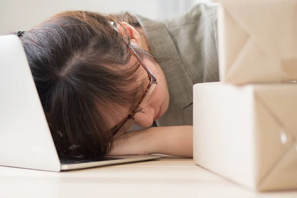 exhausted asian woman business working overnight and sleep at work desk; portrait of tired, exhausted, overworked business woman sleeping with tireness on work station; adult asian chinese woman model