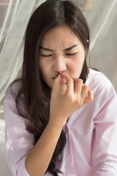 sick girl sniffle with runny nose; sick woman suffering from cold, flu, runny nose, trying to clear her nose; woman personal health care, sinus pain, sickness concept; asian young adult woman model