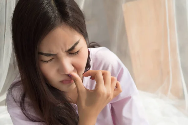 sick girl sniffle with runny nose; sick woman suffering from cold, flu, runny nose, trying to clear her nose; woman personal health care, sinus pain, sickness concept; asian young adult woman model