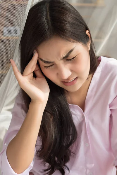 portrait of sick woman with headache; depressed woman suffers from stress, vertigo, dizziness, migraine, hangover; health care and mental health concept; 20s young adult asian woman model