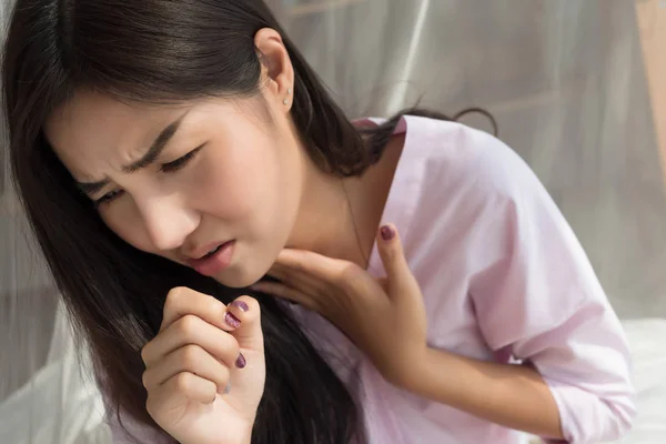woman coughing; portrait of woman suffering from cold, flu, sore throat sickness with cough symptoms; female inspiratory body care, inspiration or lung sickness concept; asian young adult woman model