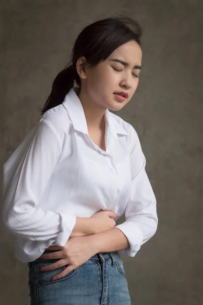 woman with stomach ache; sick woman suffering from stomachache, menstrual period cramp, abdominal pain, food poisoning, gastritis, acid reflux; asian young adult woman health care model