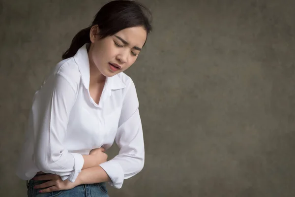 woman with stomach ache; sick woman suffering from stomachache, menstrual period cramp, abdominal pain, food poisoning, gastritis, acid reflux; asian young adult woman health care model