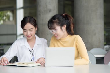 Akıllı kadın üniversite öğrencileri okula dönecek olursak; mutlu gülümseyen kadın öğrencilerin üniversite düzeyinde eğitim, sonbahar ya da kış okulu kavramı başa eğitim portresi; Asyalı Genç Yetişkin kadın modeli