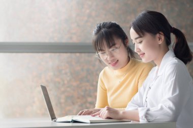 Akıllı kadın üniversite öğrencileri okula dönecek olursak; mutlu gülümseyen kadın öğrencilerin üniversite düzeyinde eğitim, sonbahar ya da kış okulu kavramı başa eğitim portresi; Asyalı Genç Yetişkin kadın modeli