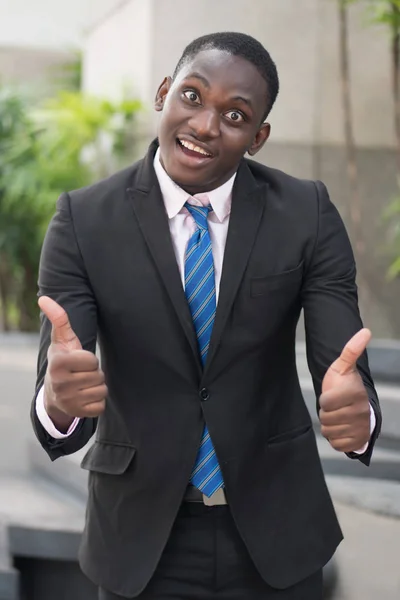 african businessman giving thumb up; portrait of successful confident african business man showing success thumb up gesture for winner, successful business deal; young adult african man model