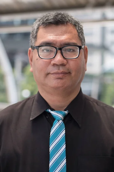 old south east asian business man face; face portrait of old senior southeast asian businessman, formal office worker with eye glasses and grey hair; south east asian middle age to senior man model