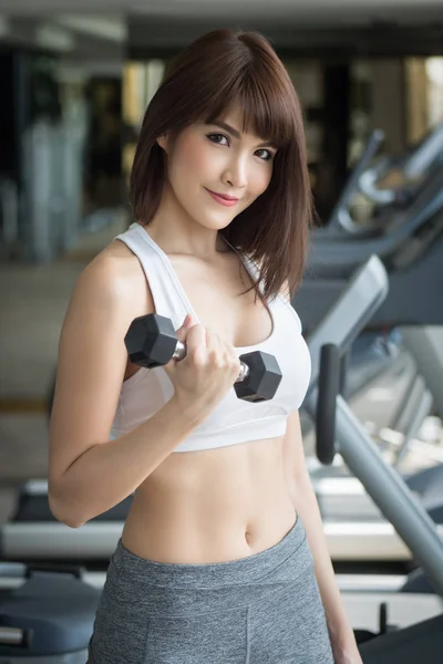 healthy strong fitness woman works out in gym. portrait of fitness woman in gym posing for strong body and arm, gym workout, weight training, healthy lifestyle concept. asian adult fitness woman model