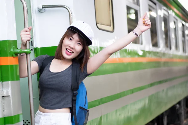 woman travels on train; portrait of asian woman traveler catching the train on train station platform, vacation travel or holiday concept; asian woman 20s adult model