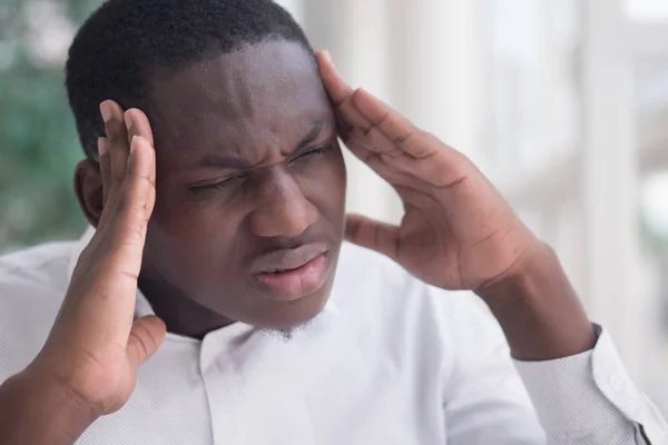 portrait of stressed sick black man with headache; ill african man suffers from headache, vertigo, dizziness, migraine, stress, depression, hangover concept; adult african man model