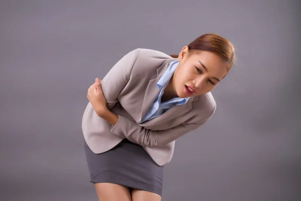 woman with stomach ache or menstruation; sick woman suffering from stomachache, menstrual period cramp, abdominal pain, food poisoning, gastritis, acid reflux; asian young adult, tan skin woman model