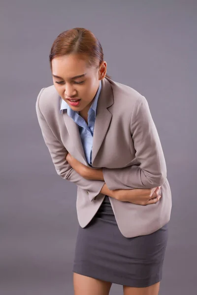 woman with stomach ache or menstruation; sick woman suffering from stomachache, menstrual period cramp, abdominal pain, food poisoning, gastritis, acid reflux; asian young adult, tan skin woman model