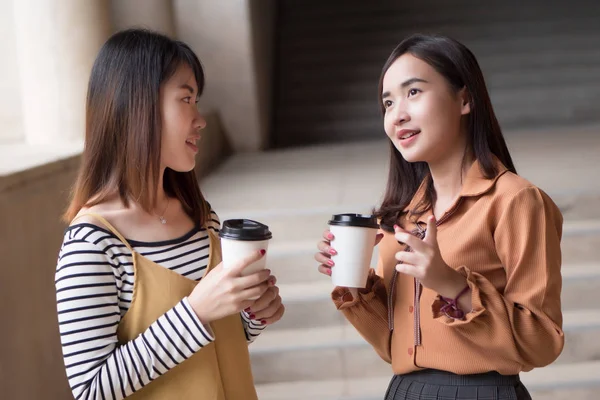 asian woman friend talking about gossip; portrait of two friendly woman drinking coffee while gossiping, concept of friendship, social trend, casual news update; young adult asian woman model