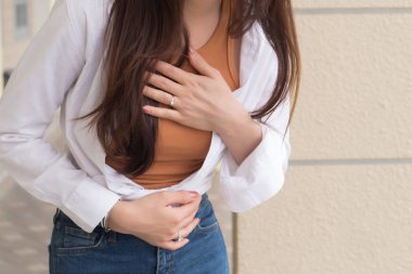 hazımsızlık sorunu, asit reflü veya mide belirtileri ile hasta bir kadın; kadın sağlık bakımı, vücut bakımı, hastalık, ağrı, asit reflü kavramı; 20'li yaşlarda Genç Yetişkin Asyalı kadın modeli