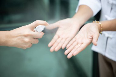 Palmiye derisindeki mikropları öldürmek için alkol el spreyi kullanan insanlar; el dezenfeksiyonu için alkol spreyi, yüzey dezenfektanına dokunmak, Coronavirus covid-19 için el dezenfektanı, sağlık hizmetleri
