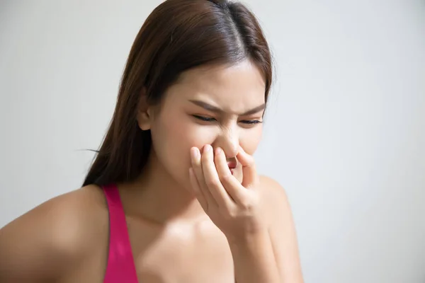 asian woman covering her nose for bad smell, concept of stink thing, bad breath, unpleasant smell, rotten food, odor, body bad smell; young adult southeast asian woman model
