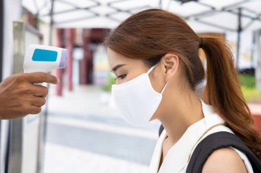 woman wearing face mask getting infrared thermal scanned for fever at check point clipart